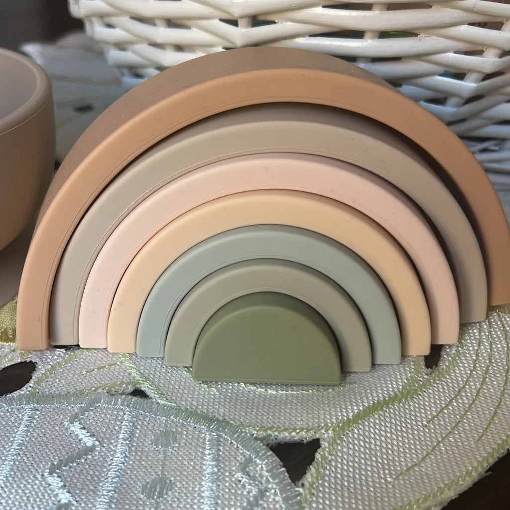 Neutral Rainbow stacking toy with white basket in back ground.