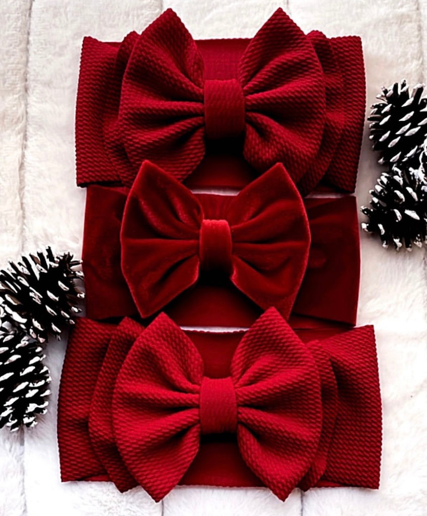 Three red bows flat lay with pine cones in back ground.