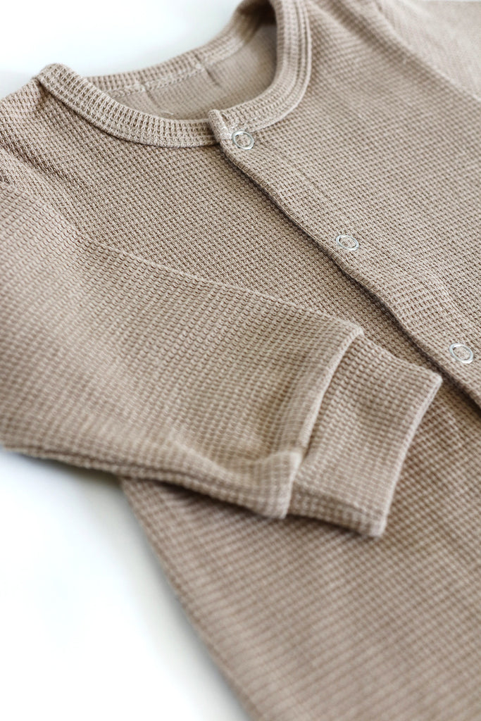 Folded beige baby sweater on a white background