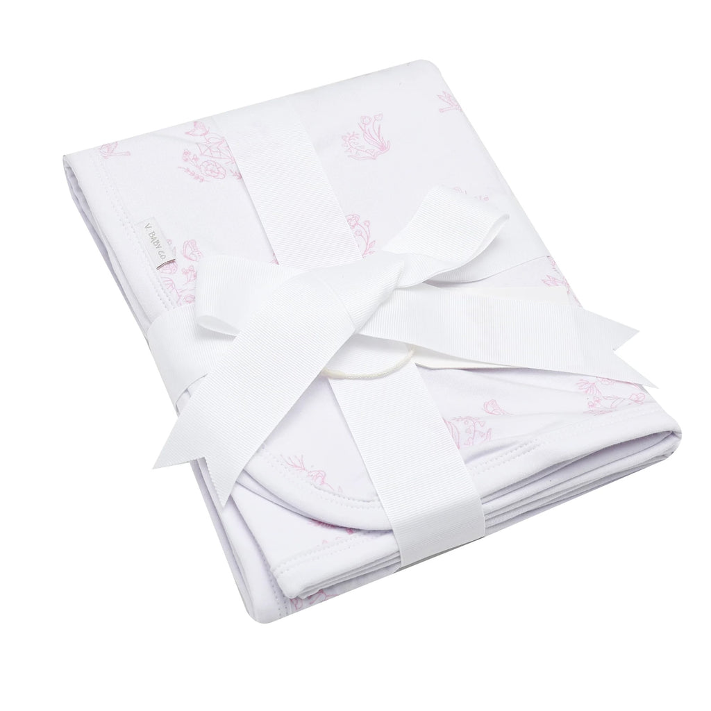 Pink and white Blanket with white bow tied around it flat lay